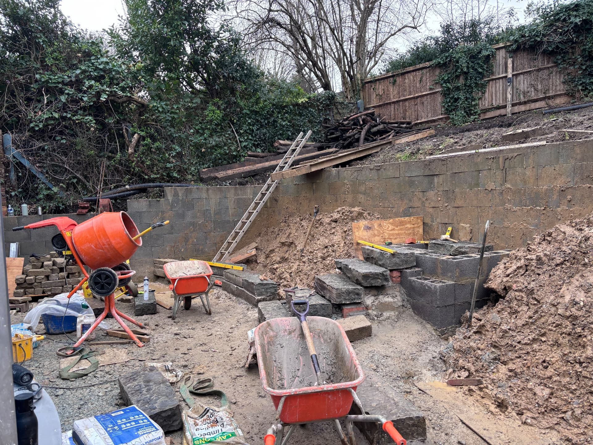 Terraced garden mid-build with mixer, barrows and block retaining walls