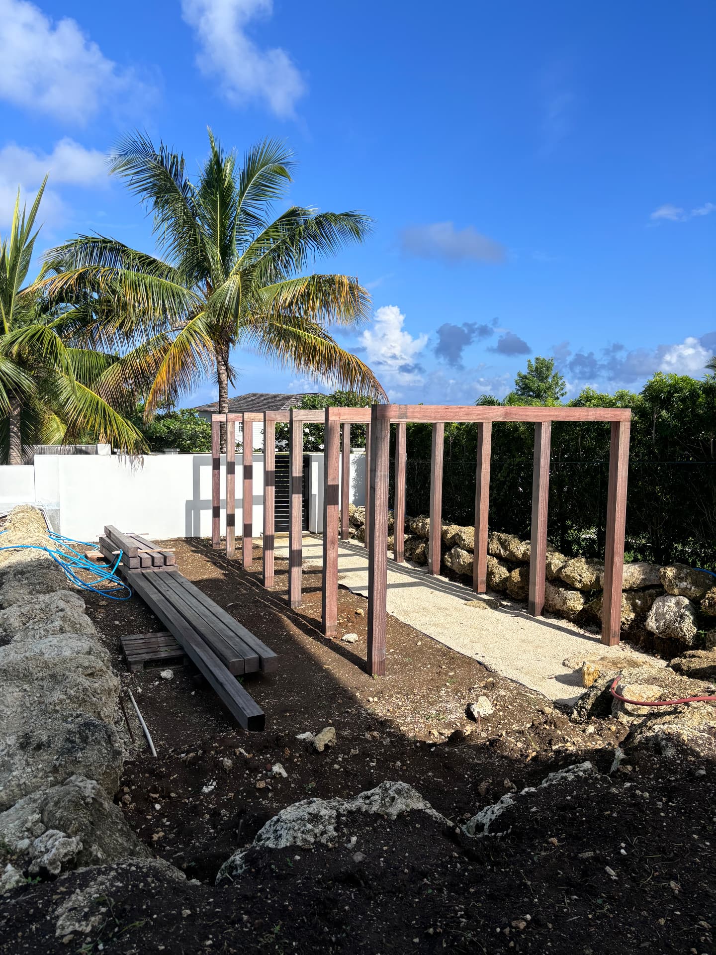 Purpleheart pergola frame standing over gravel between coral stone boulders