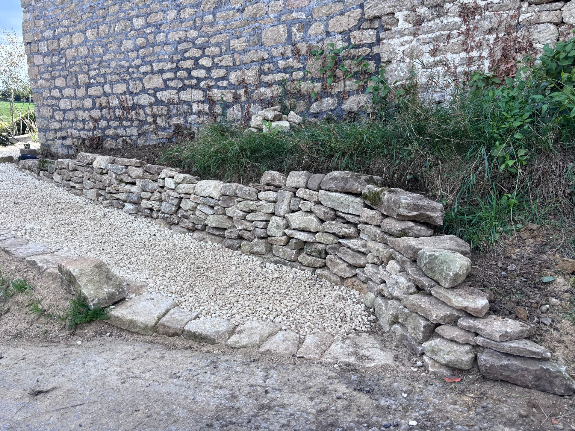 Newly built drystone retaining wall with stone setts and gravel at Studio Garden, Somerset
