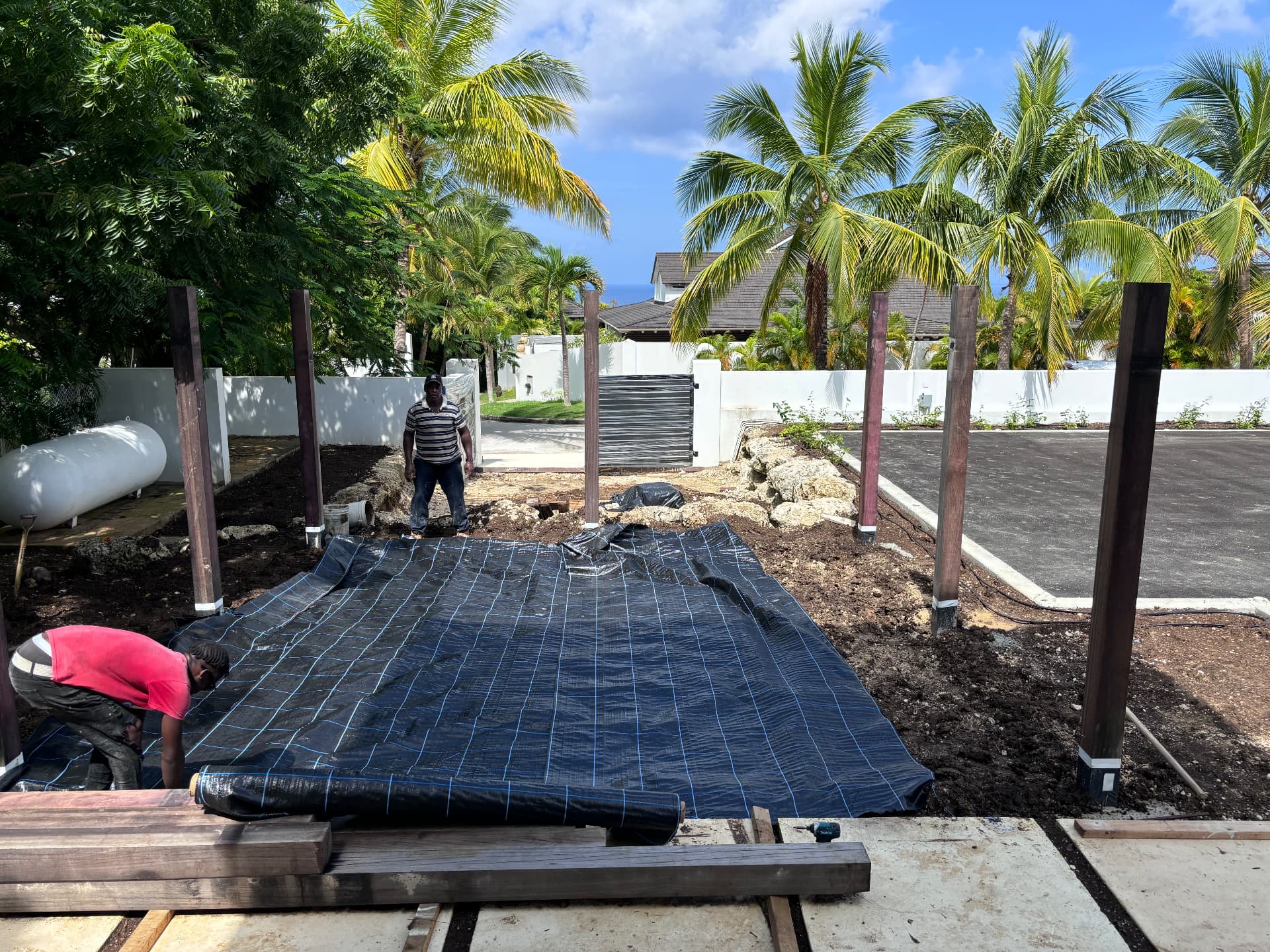 Laying weed membrane between pergola posts with the sea beyond