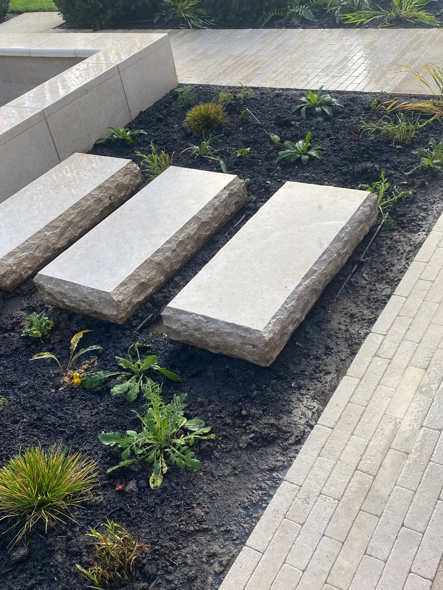 Split-face stone stepping slabs set through a freshly mulched planting bed