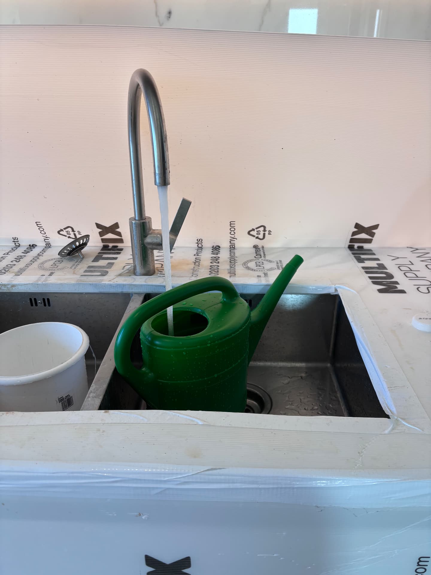 Filling a watering can on site during a garden installation