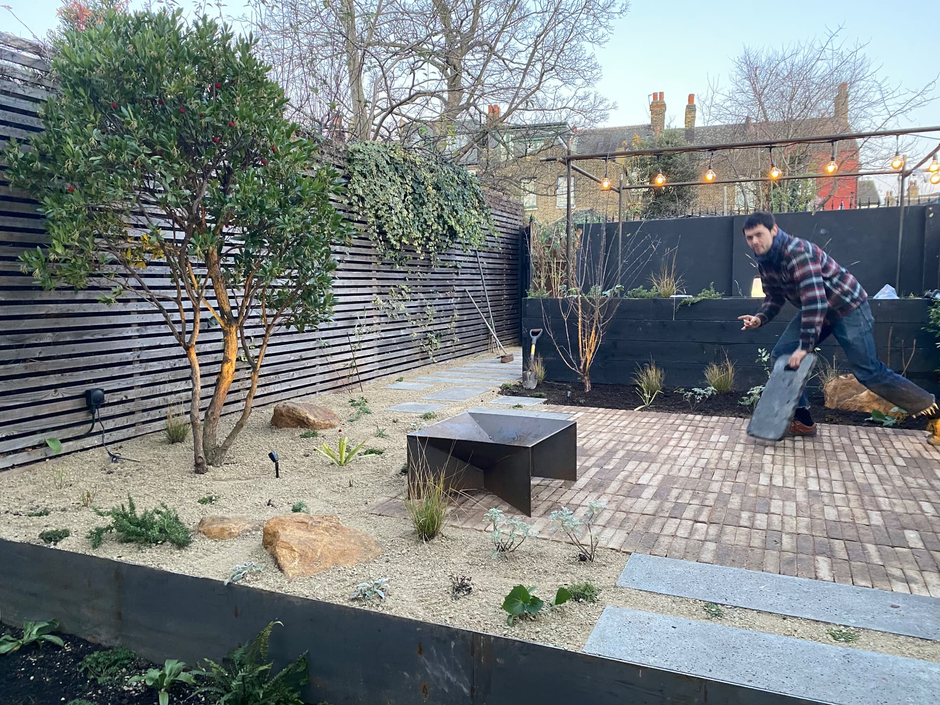 Setting a stone slab into a London courtyard of gravel, brick paving and a steel fire table