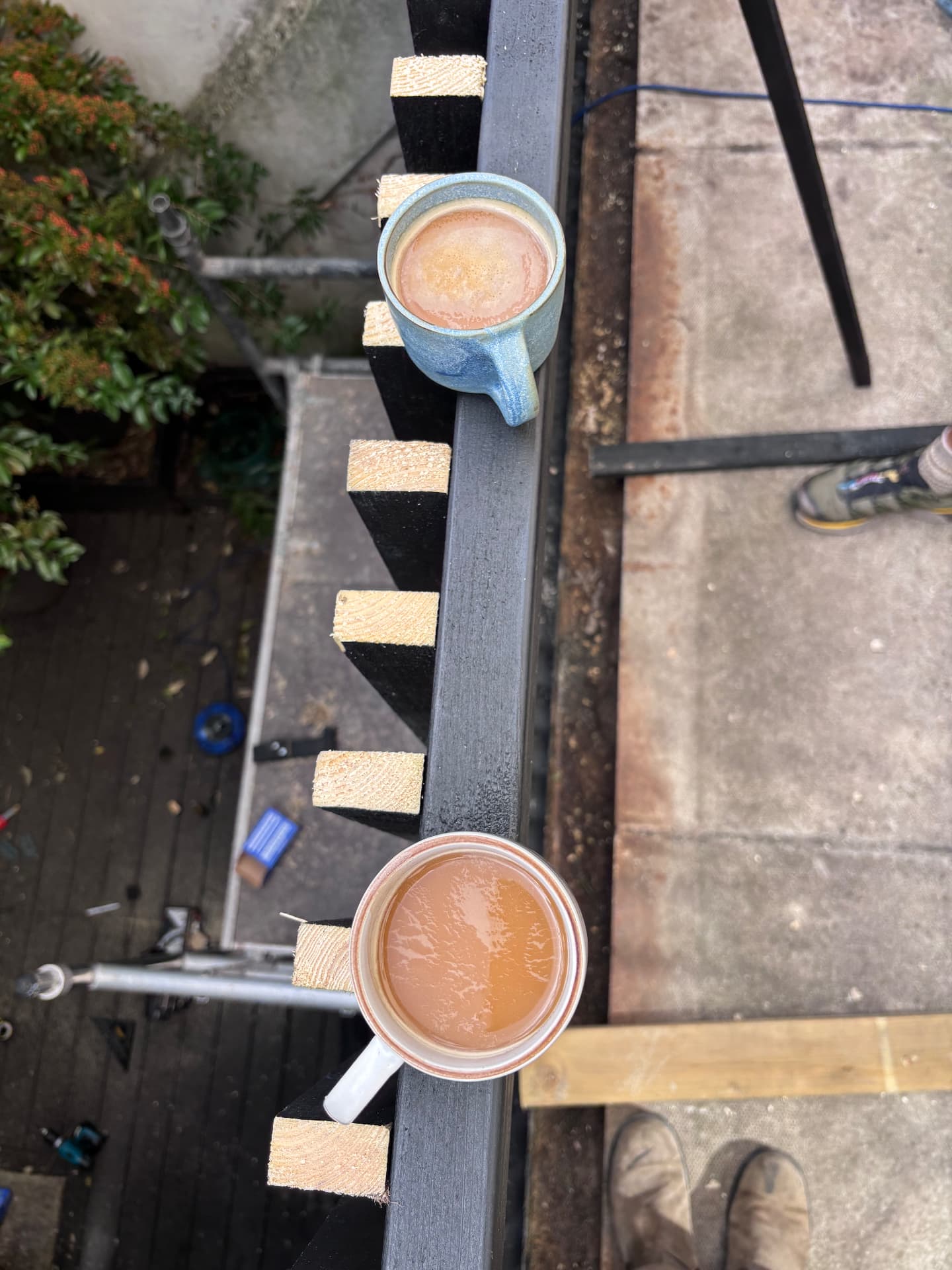 Two mugs of tea resting on a freshly cut deck joist during the build