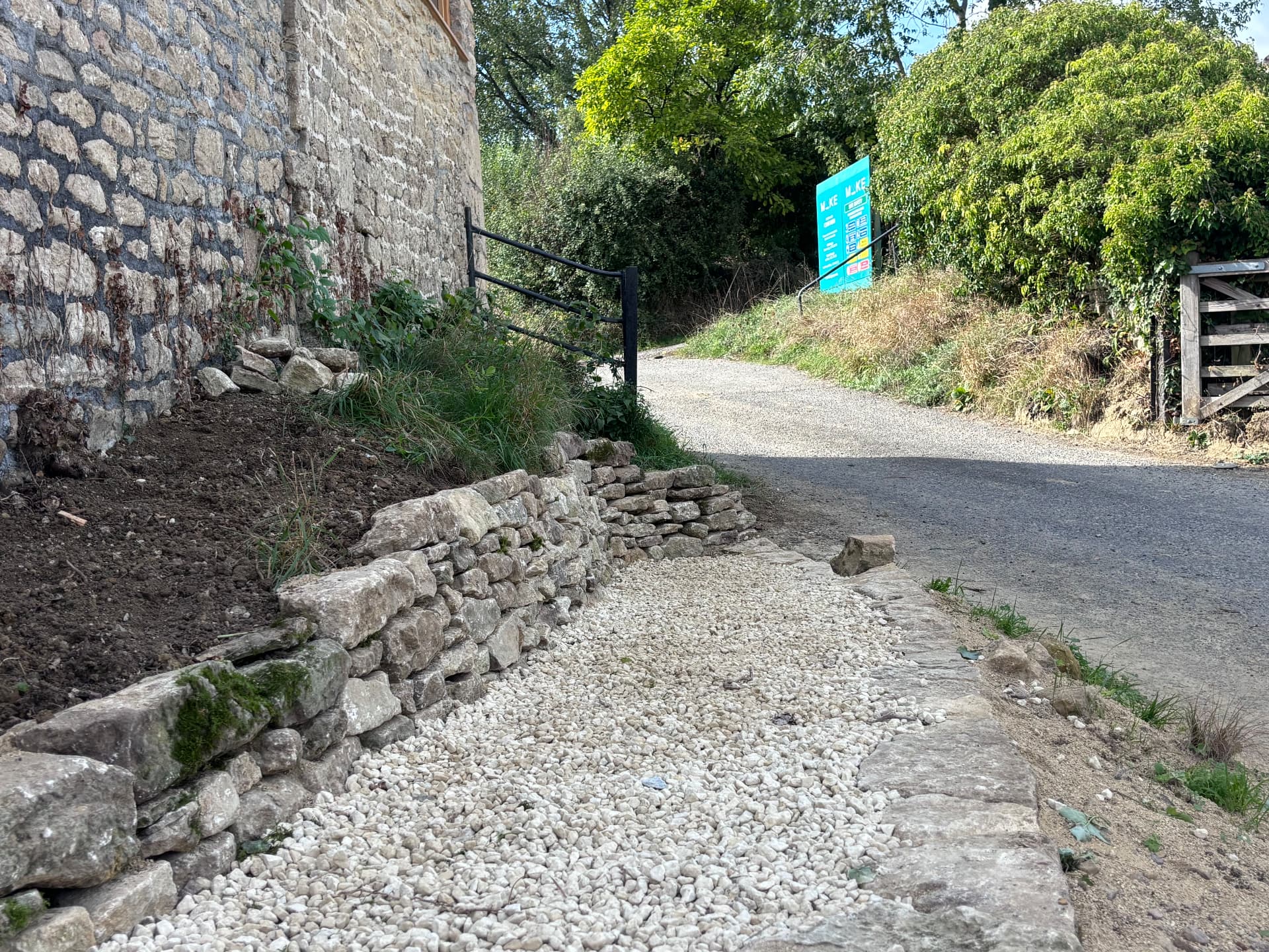 Low drystone wall edging the gravel entrance beside the lane at Studio Garden, Somerset