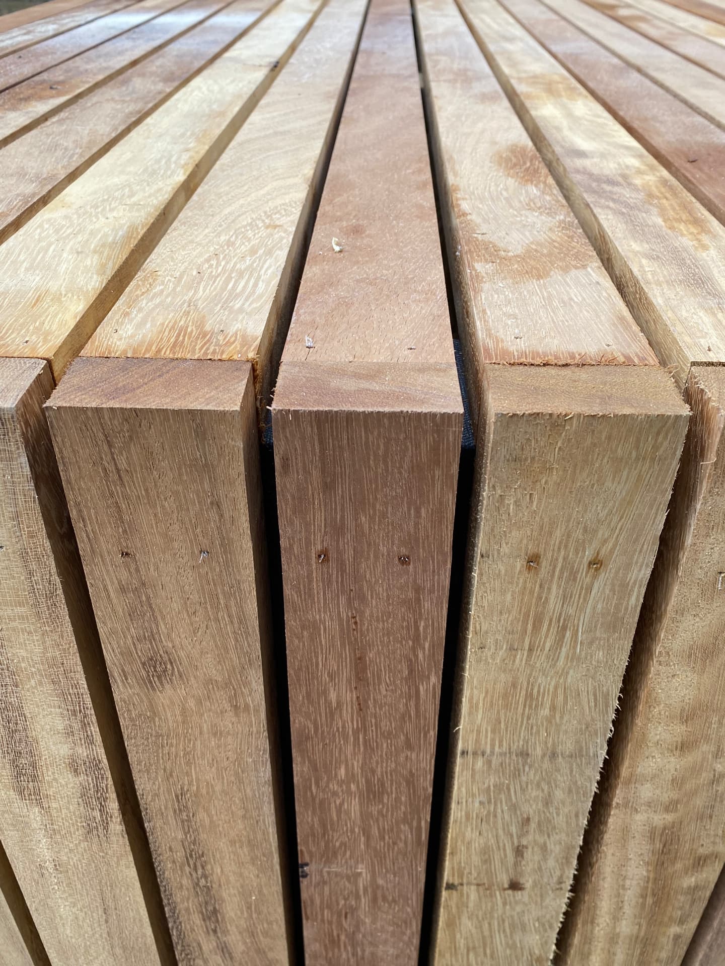 Freshly sawn hardwood decking boards stacked, showing grain and warm tones