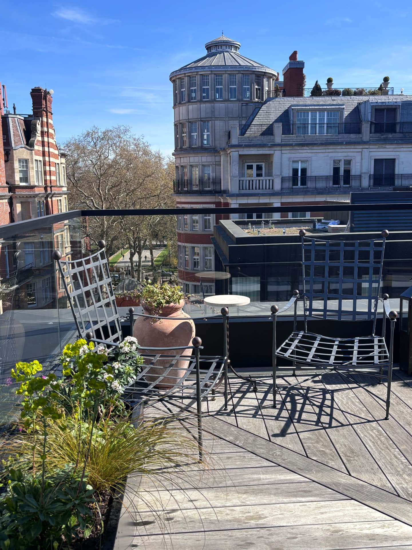 Roof terrace seating with terracotta jar, euphorbia and grasses in spring sun